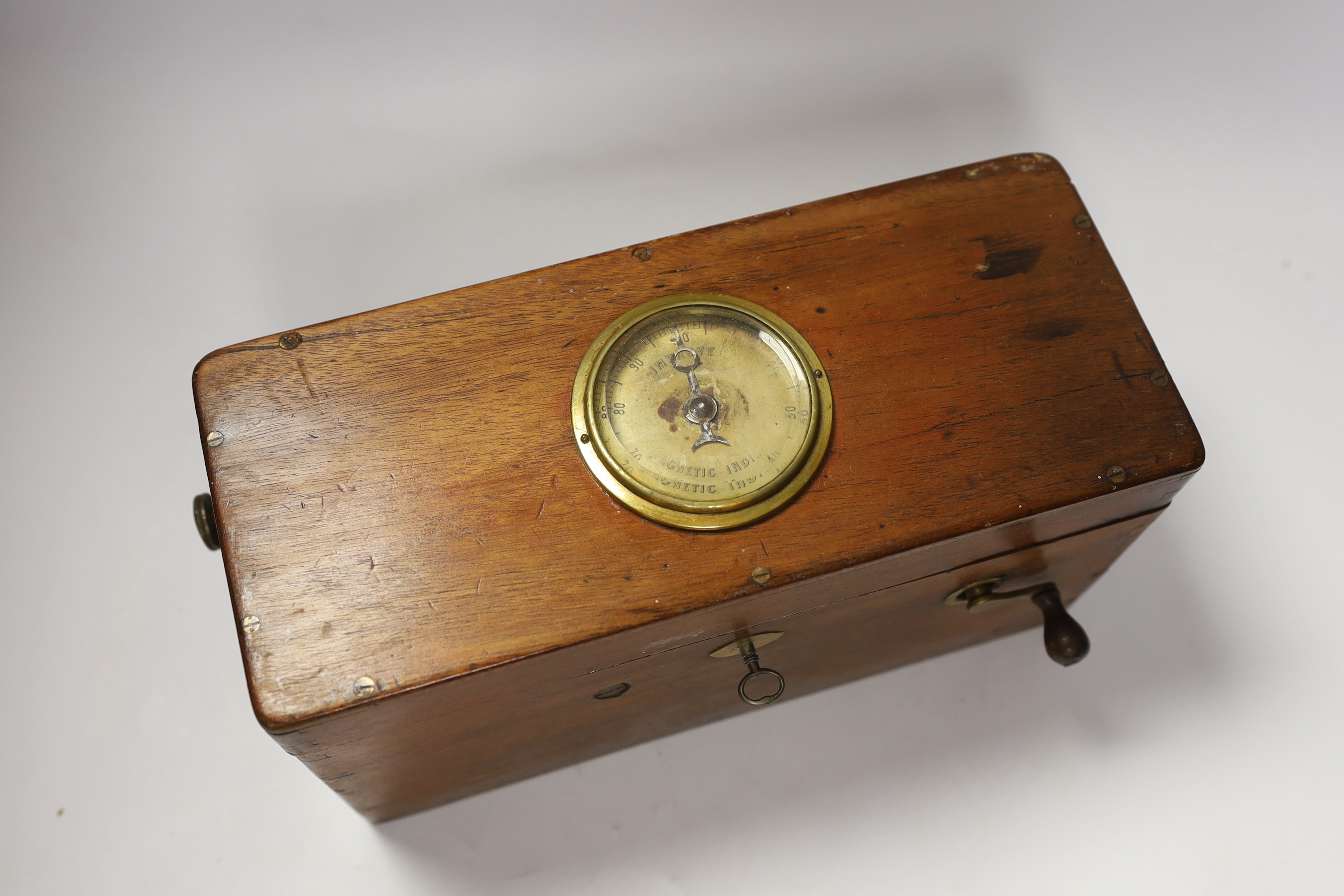 A Magneto electric shock machine in a mahogany case with output gauge to lid and built-in drawer containing a range of alternative fittings and implements with ebonised handles, lock with original key, 16.5cm high, 30cm
